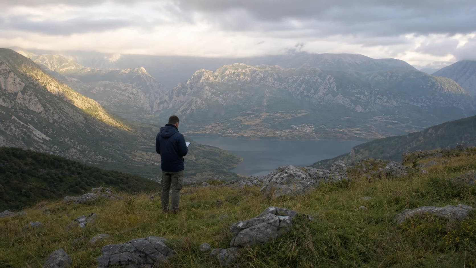 Anonymous figure observing the mountain and lake territory of Kukës